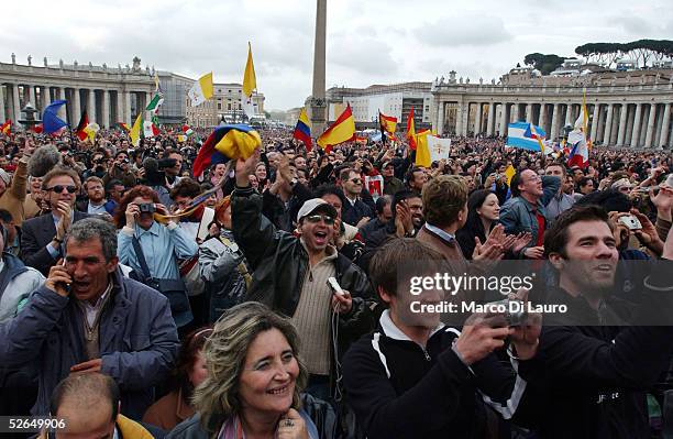 The crowd reacts as white smoke rises from the Sistine Chapel, signaling a new pope has been elected, during the second day of the conclave April 19,...