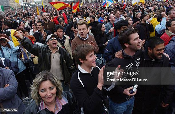 The crowd reacts as white smoke rises from the Sistine Chapel, signaling a new pope has been elected, during the second day of the conclave April 19,...