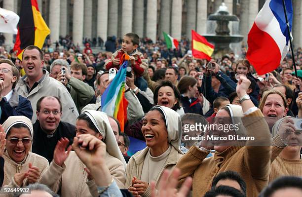 Nuns react as white smoke rises from the Sistine Chapel, signaling a new pope has been elected, during the second day of the conclave April 19, 2005...