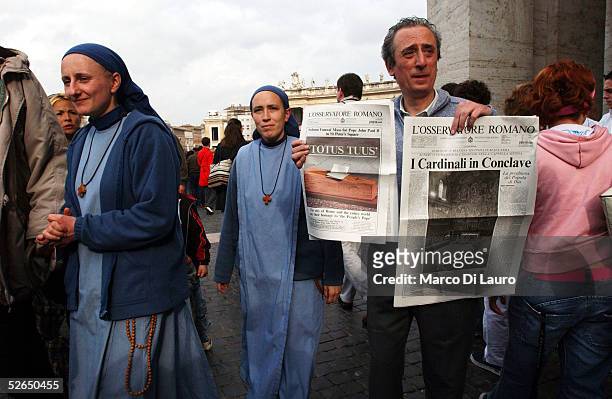 Two nuns pass by a vendor selling "L'Osservatore Romano" the Vatican newspaper as they wait for the smoke to rise from the Sistine Chapel during the...