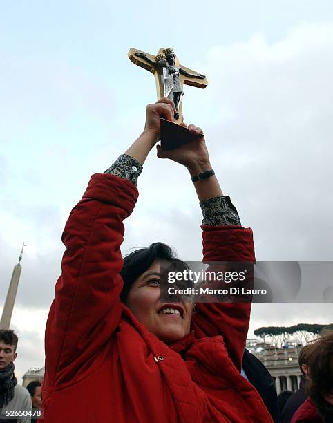 Woman displays a crucifix as German Cardinal Joseph Ratzinger appears on the balcony of St.Peter's Cathedral as Pope Benedict XVI at the end of the...