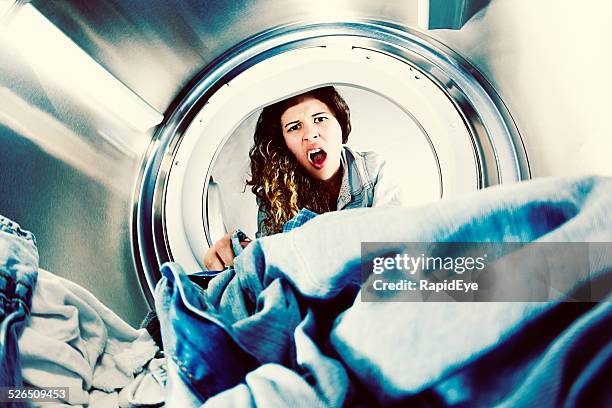 horrified young woman grimaces at laundry in clothes drier - smelly laundry stock pictures, royalty-free photos & images