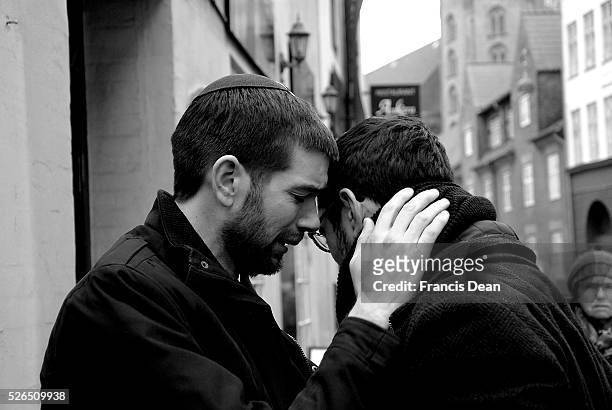 Copenhagen-Denamrk_Two danish male jews comfort each other with hugs and embressing one and other at synagogue today shed tears and griefs and sorrow...