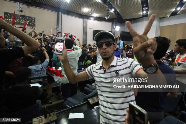 An Iraqi man shows on his smartphone a picture of Shiite cleric Moqtada al-Sadr as protesters gather inside the parliament after breaking into...