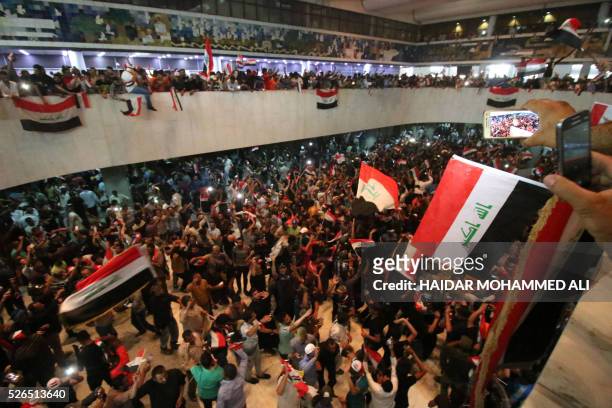 Iraqi protesters wave national flags as they gather inside the parliament after breaking into Baghdad's heavily fortified "Green Zone" on April 30,...
