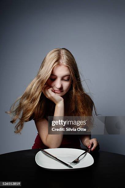 pretty girl staring at empty plate - weight gain foto e immagini stock