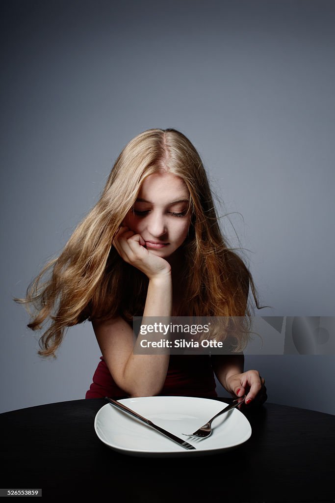 Pretty girl staring at empty plate
