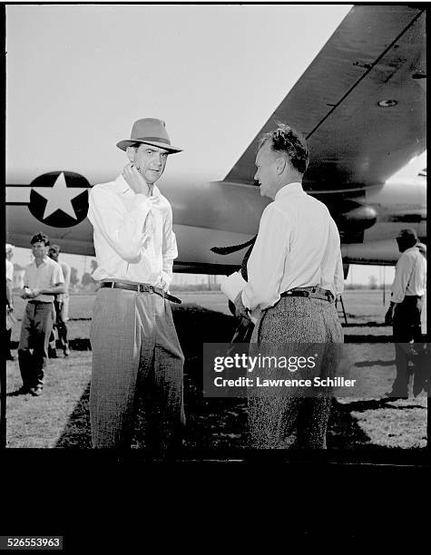 American businessman and aviator Howard Hughes speaks with an unidentified man by the fuselage of a US military plane, Long Beach, California, 1947.