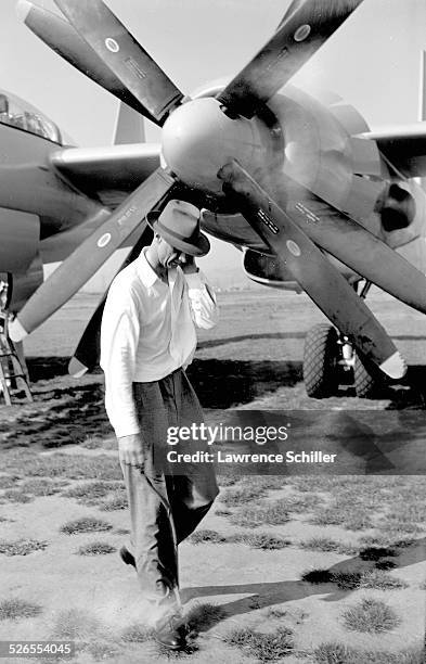 American businessman and aviator Howard Hughes walks past the propeller of one of his airplanes, Los Angeles, California, 1947.