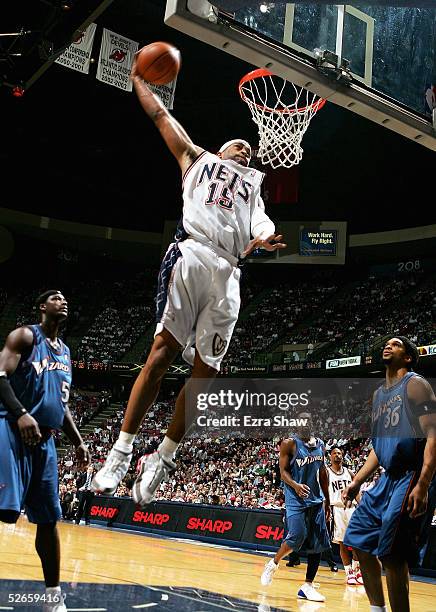 Vince Carter of the New Jersey Nets slam dunks the ball over Etan Thomas and Kwame Brown of the Washington Wizards on April 19, 2005 at Continental...