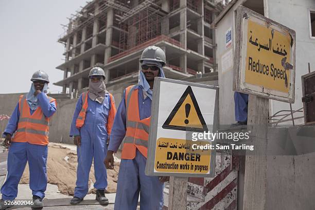 Migrant construction workers pose for a picture outside of their work site at The Pearl, a man-made chain of islands off the coast of northern Doha,...