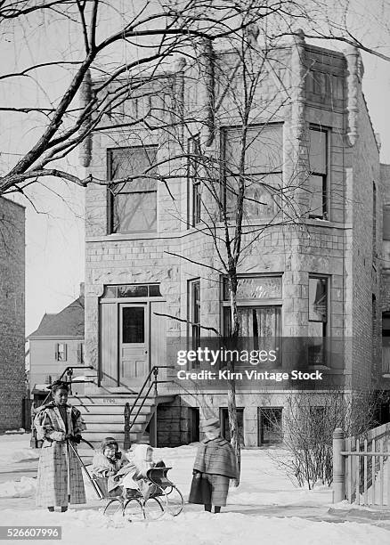 An African-American nanny poses with the two children in front of a home on Chicago's South Side at the turn of the century.