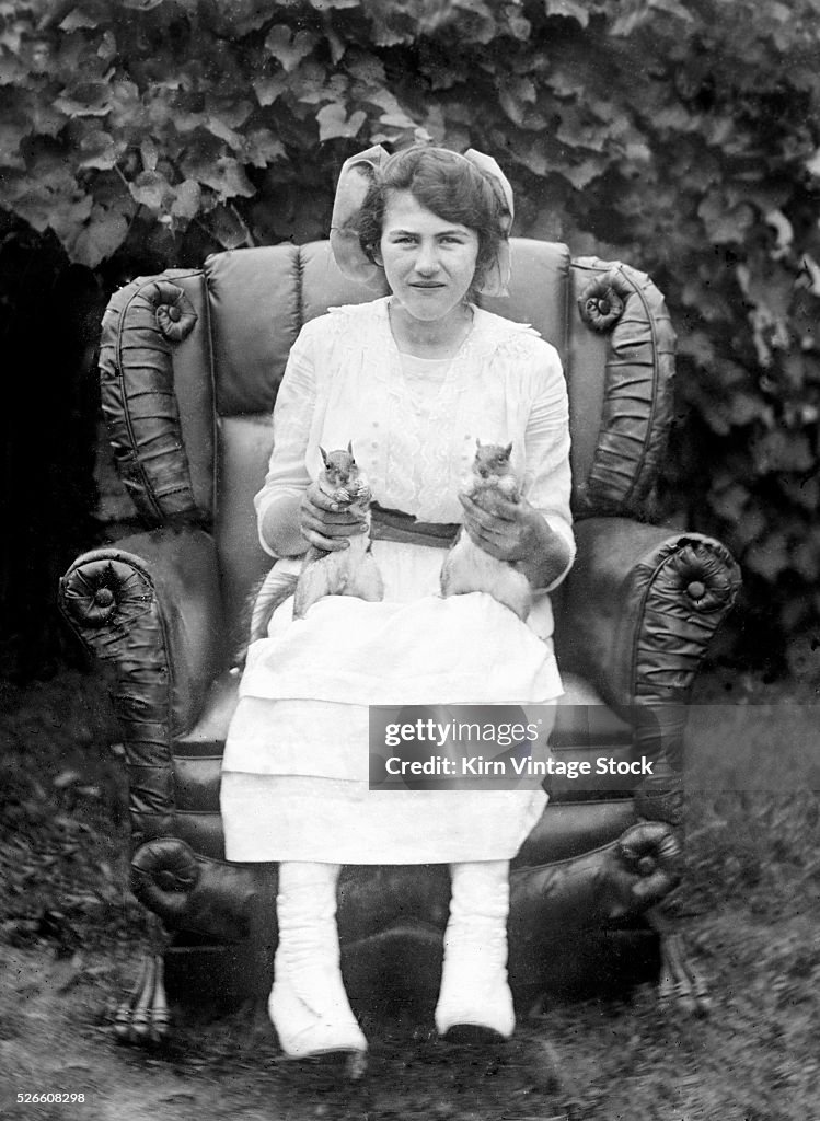 A woman sits with her two squirrelly friends, ca. 1905.