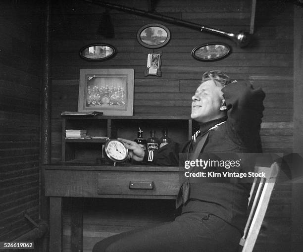 Young naval recruit holds clock in his barracks and appears to have forgotten what time it was and where he was supposed to be.