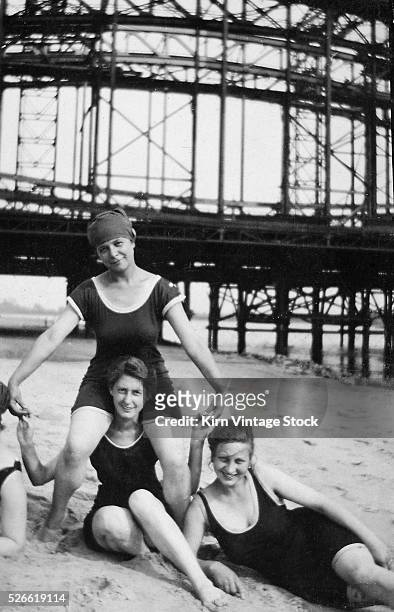 Three young women group together on the beach, ca. 1925.