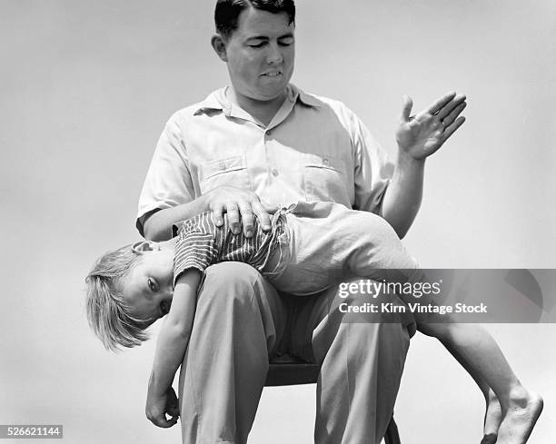 Young boy receives a spanking from his father in this staged photograph.