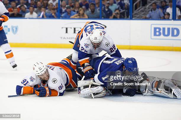 Thomas Greiss of the New York Islanders makes the save as Alex Killorn of the Tampa Bay Lightning gets knocked down by John Tavares of the New York...