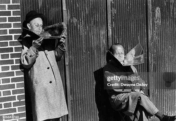 Two old men using reflectors to catch sun rays, 1940's NYC