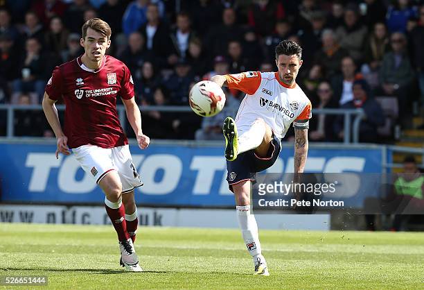 Alan Sheehan of Luton Town plays the ball watched by John Marquis of Northampton Town during the Sky Bet League Two match between Northampton Town...