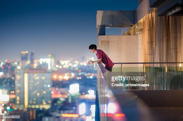 homem de pé no telhado de um arranha-céu de vista da cidade - high up imagens e fotografias de stock