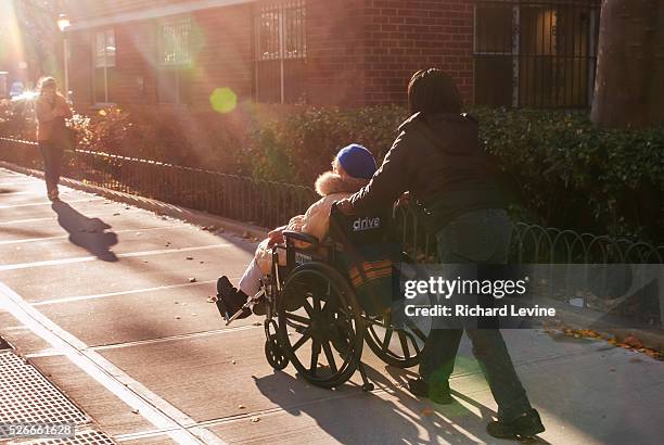 Elderly woman in her wheelchair is assisted by an aide in the New York neighborhood of Chelsea on Wednesday, December 5, 2012. Social Security,...