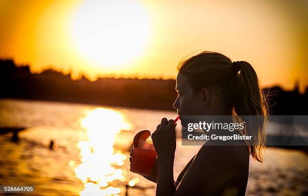 frau trinkt cocktail - cocktail sonnenuntergang stock-fotos und bilder