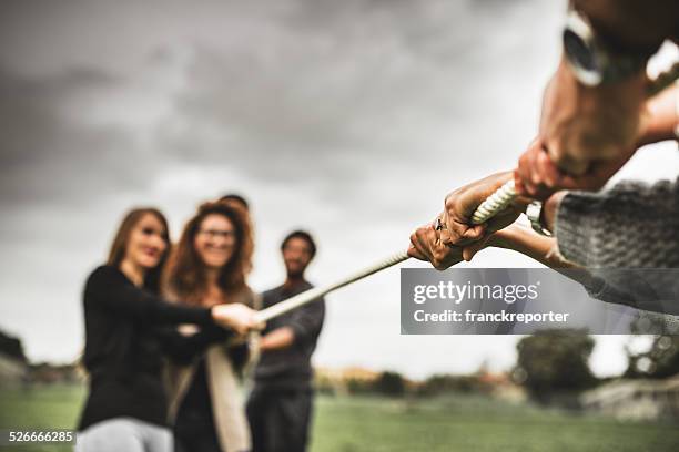 amigos haciendo la cuerda de guerra de trabajo en equipo - lucha de la cuerda fotografías e imágenes de stock