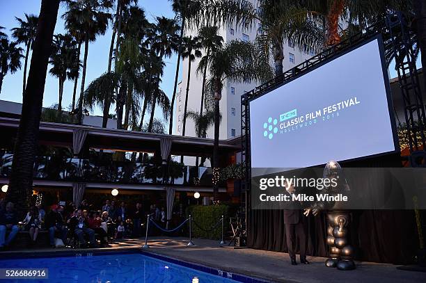 Image was shot in HDR.) LOS ANGELES, CA Actor Greg Proops and Robby the Robot speak onstage at 'Forbidden Planet' screening during day 3 of the TCM...