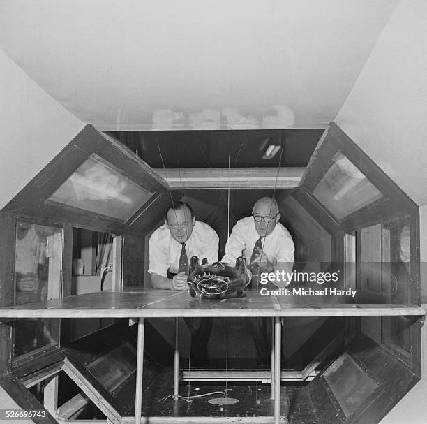 British speed record breaker Donald Campbell with his chief engineer Leo Villa testing a model of the Bluebird car in a wind tunnel, 1st August 1958.