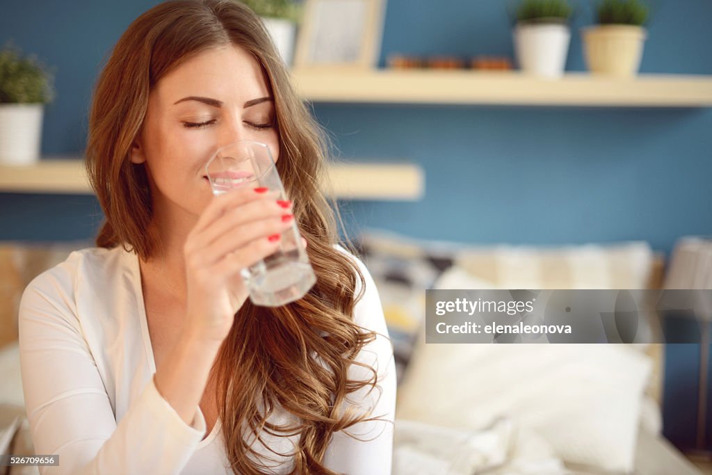 Mujer joven hermosa sostiene un vaso de agua