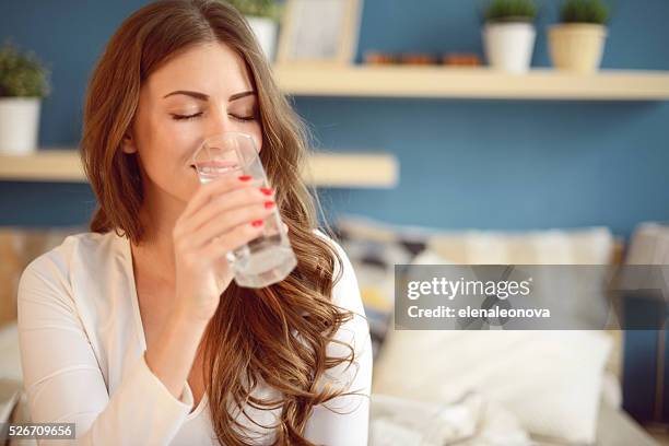 beautiful young woman holding a glass of water - beautiful women bed stockfoto's en -beelden