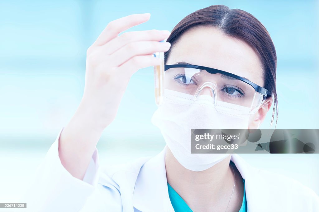 Young female researcher using microscope at office