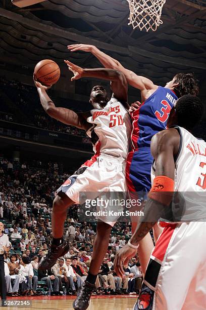 Emeka Okafor of the Charlotte Bobcats gets up in the air and avoids a block by Darko Milicic of the Detroit Pistons on April 20, 2005 at the...