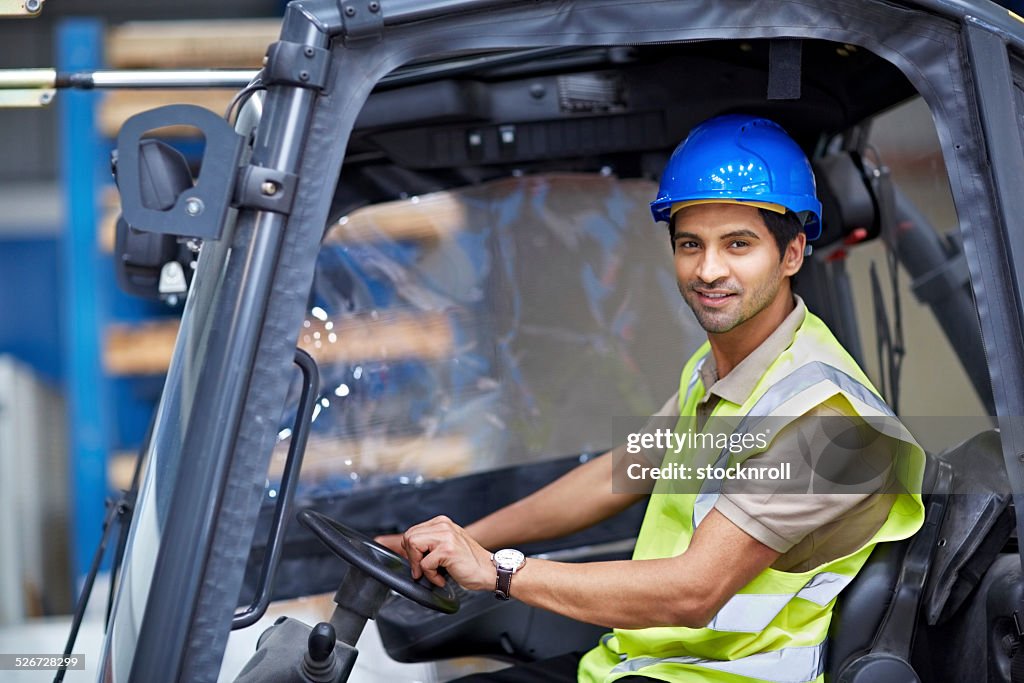 Man driving fork lift truck in warehouse