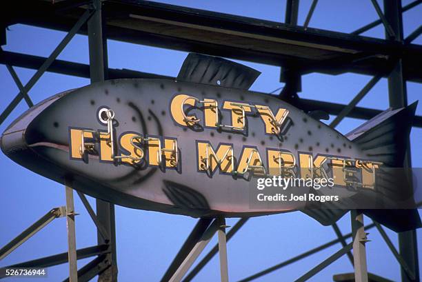 Fish shaped sign with neon letters announces the City Fish Market at the Pike Place Market. Seattle, Washington, USA.