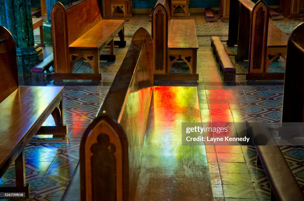 Colored light from stain glass windows glow on Costa Rican church pews