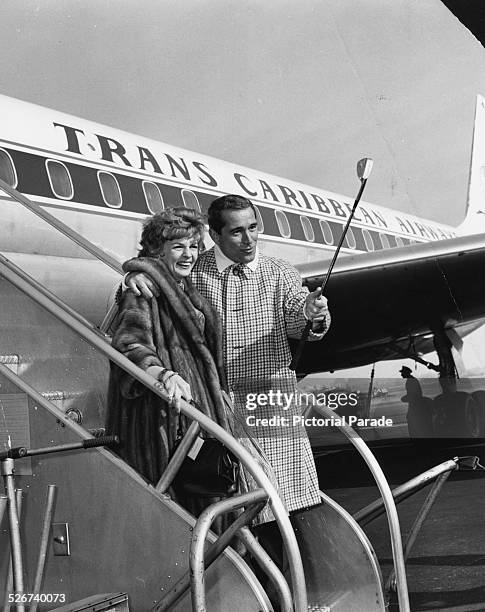 Singers Perry Como and Dorothy Collins smiling on the steps of an airplane, boarding a flight to Guantanamo Naval Base to perform for the personnel,...