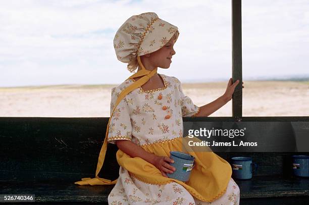 Young girl on a vacation designed to simulate the experience of pioneers on the Oregon Trail wears a costume of the style worn by pioneer girls. Near...