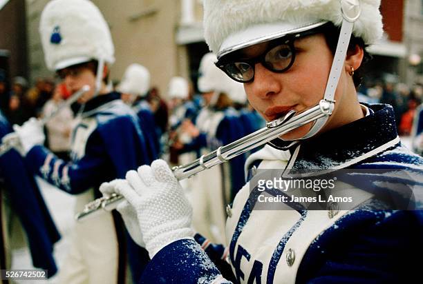 Teenage girl plays the flute in a marching band at the Saranac Lake Winter Carnival.