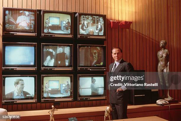 Italian politician and businessman, Silvio Berlusconi, beside an array of televisions, May 1986. .