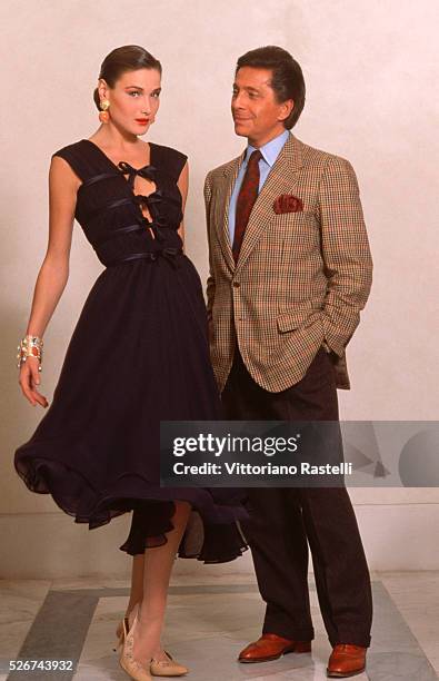 Valentino stands beside a model wearing a black dress in Rome, Italy.