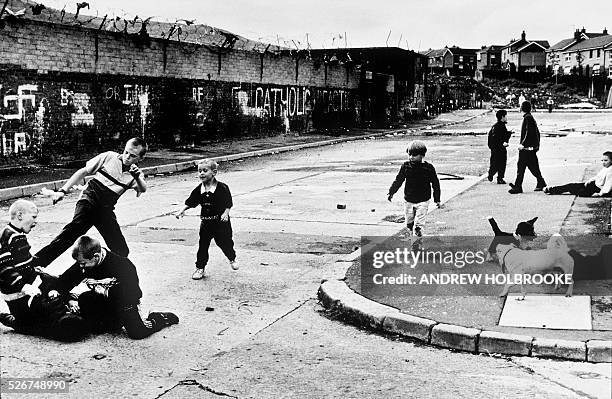 Catholic children fight amongst themselves in the Falls Road section of West Belfast. The "Peace Wall" dividing Catholics and Protestants is seen...