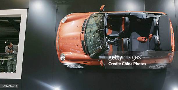 Chinese man views a Mini Cooper hung on the wall at the Auto Shanghai 2005 Exhibition on April 21, 2005 in Shanghai, China. Top world automakers will...