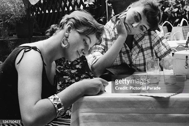Actresses and siblings Jackie Collins and Joan Collins catching up on correspondence while on location making the film 'Land of the Pharaohs', 1955.