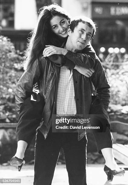 Portrait of actor John Nettles, with actress Cecile Paoli on his back, both stars of the new television series 'Bergerac', October 7th 1981.