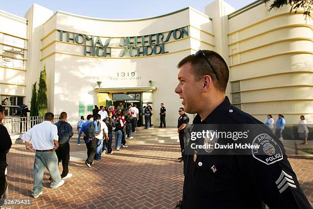 Los Angeles School Police Sgt. Robert Carlborn watches over students lining up to pass through a security check point in the aftermath of two...