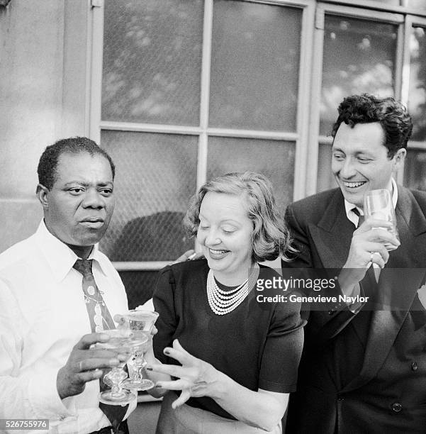 Louis Armstrong celebrates his 50th Birthday with Tallulah Bankhead and Bill Langford on the terrace of Bankhead's New York City apartment.