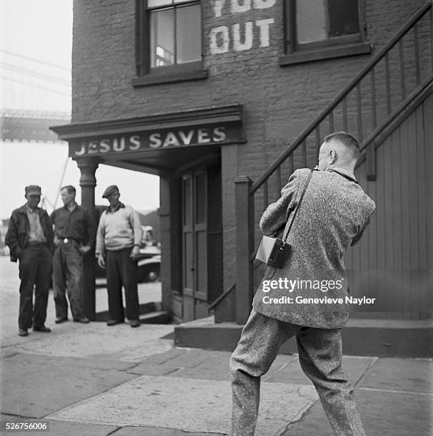 Henri Cartier-Bresson photographs three men under a "Jesus Saves" sign in Brooklyn. Cartier-Bresson's work on the streets of Brooklyn was documented...