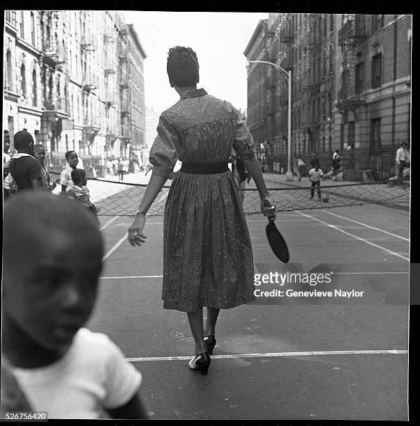 Tennis champion Althea Gibson plays paddle ball with kids on a Harlem street.