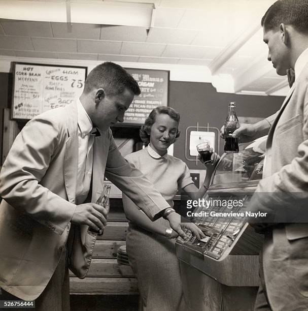 College students drinking soft drinks at a diner make selections on a jukebox. Long Island, 1954.